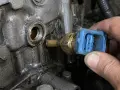 Błąd czujnik temperatury płynu chłodzącego. Mechanik wymienia uszkodzony czujnik w silniku.