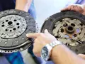 Mechanik pokazuje dwa dyski sprzęgła: jeden nowy, drugi mocno zużyty, z widocznymi śladami spalonego sprzęgła.