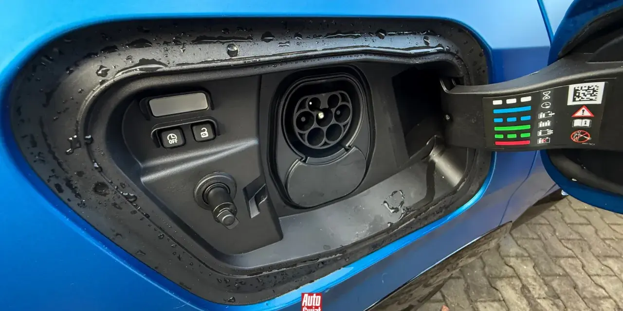 Gniazdo ładowania w niebieskim samochodzie. To pokazuje, co to jest plug-in hybrid – samochód, który można ładować z sieci.