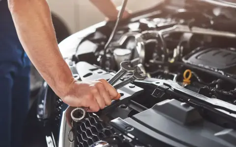 Mechanik sprawdza objawy awarii pompy paliwa Audi A4 B6 1.8T. W dłoni trzyma klucze.