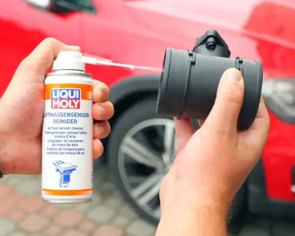 Czyszczenie przepływomierza: ręka trzyma puszkę preparatu Liqui Moly i aplikuje go na element.