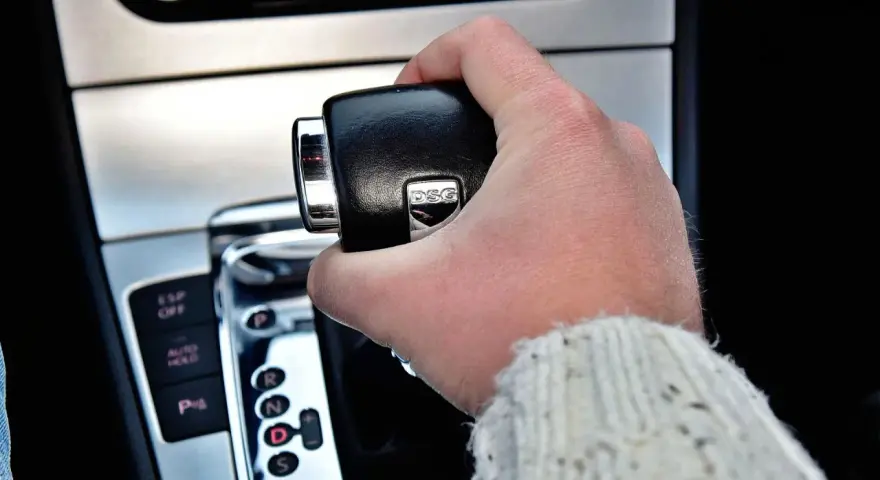 Dłoń trzymająca dźwignię zmiany biegów. Widoczny napis DSG, sugerujący skrzynię automatyczną.