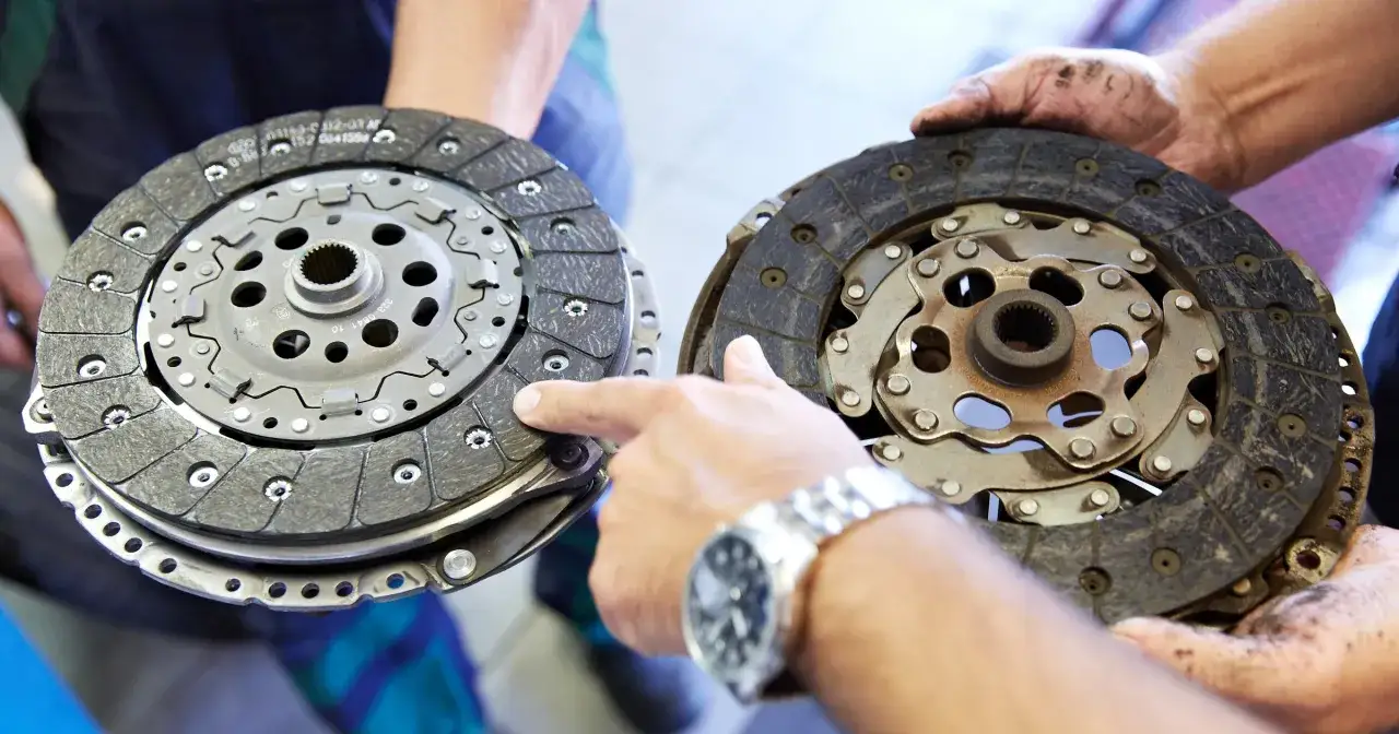 Mechanik pokazuje dwa dyski sprzęgła, jeden nowy, drugi mocno zużyty, z widocznymi śladami spalonego sprzęgła.